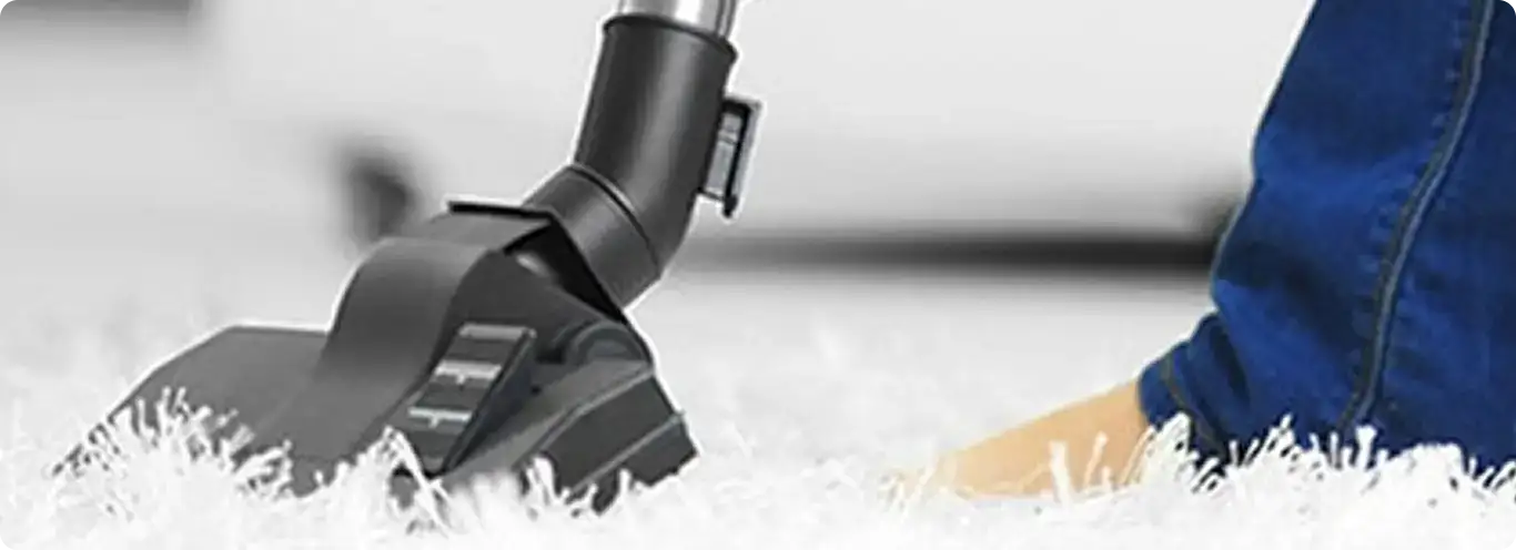 Close-up of a professional vacuuming a white carpet in Greenwich.